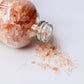 Pink bath salts pouring out of bottle 