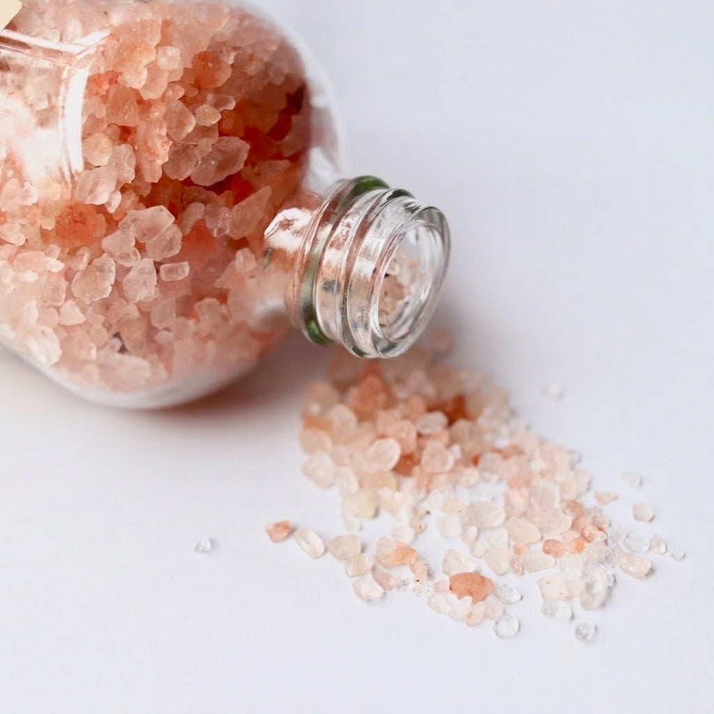 Pink bath salts pouring out of bottle 
