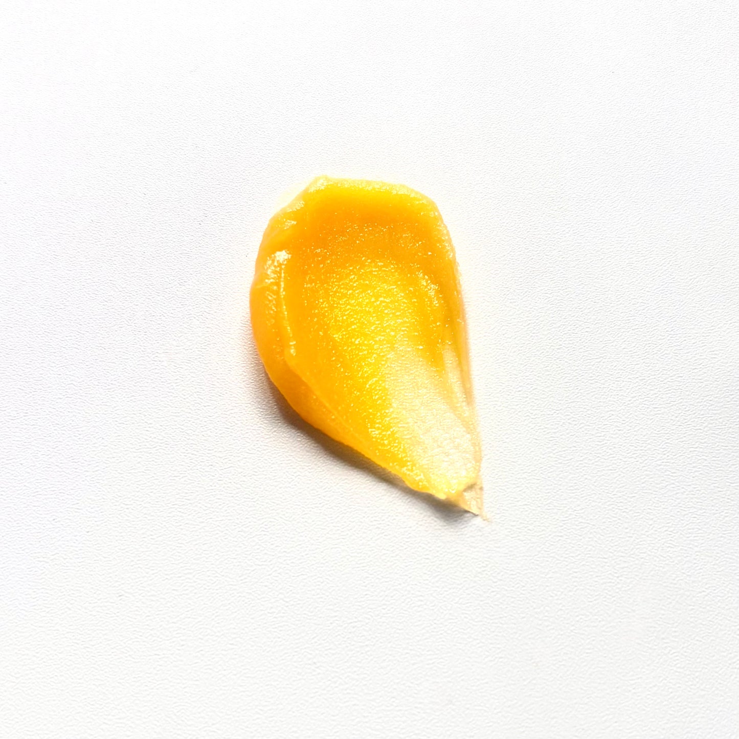 A small amount of shimmering golden-yellow cream on a plain white background.